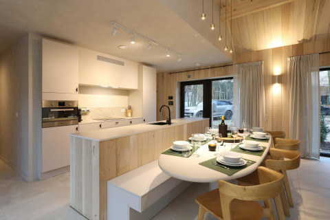 Cocina y comedor modernos con detalles en madera y mesa puesta en Villa Lodge con Jacuzzi en Woodz Lodges, Bélgica.