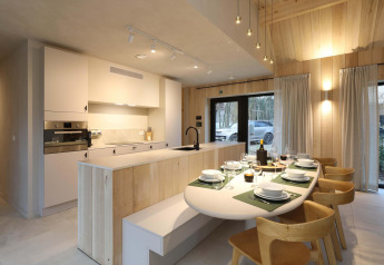 Cocina y comedor modernos con detalles en madera y mesa puesta en Villa Lodge con Jacuzzi en Woodz Lodges, Bélgica.