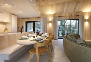 Essbereich und offene Küche in der Villa Lodge mit Whirlpool, Woodz Lodges, Belgien, mit Blick nach außen.