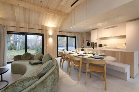 Sala y cocina moderna en Villa Lodge con jacuzzi en Woodz Lodges, Bélgica, con ventanales y madera clara.
