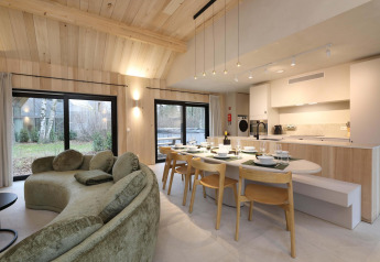 Moderne stue og køkken i Villa Lodge med jacuzzi hos Woodz Lodges i Belgien, lyse træpaneler og udsigt.