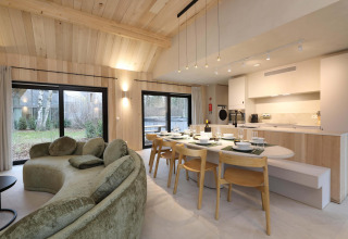 Sala y cocina moderna en Villa Lodge con jacuzzi en Woodz Lodges, Bélgica, con ventanales y madera clara.