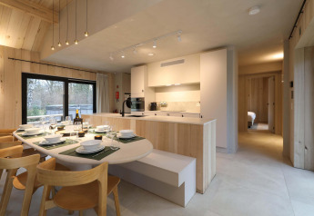 Moderne køkken og spiseområde i Villa Lodge med jacuzzi ved Woodz Lodges, Belgien, med lys træindretning.