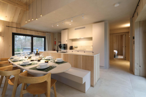 Cocina moderna y comedor en Villa Lodge con jacuzzi en Woodz Lodges, Bélgica, con decoración de madera clara.