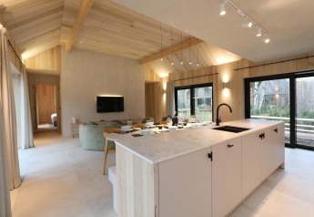 Moderne lodge-stue og køkken i Villa Lodge med Jacuzzi hos Woodz Lodges, Belgien, med store vinduer.