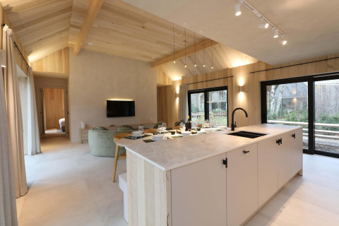 Moderna sala y cocina de la Villa Lodge con Jacuzzi en Woodz Lodges, Bélgica, con ventanales grandes.