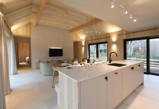 Moderna sala y cocina de la Villa Lodge con Jacuzzi en Woodz Lodges, Bélgica, con ventanales grandes.