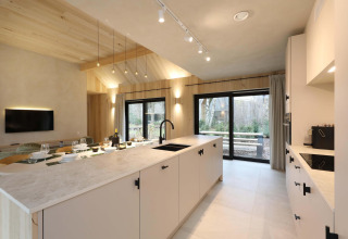 Moderne keuken en eetruimte in Villa Lodge met jacuzzi bij Woodz Lodges in België, met ruime raampartijen.