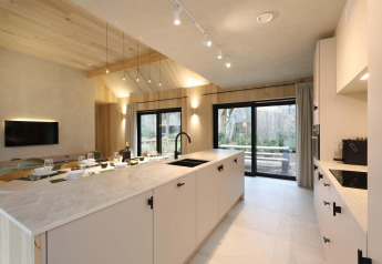 Moderne køkken- og spisestue i Villa Lodge med Jacuzzi hos Woodz Lodges i Belgien, med store vinduer.