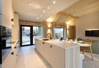 Moderne open keuken en leefruimte in Villa Lodge met jacuzzi bij Woodz Lodges, België, met veel licht.