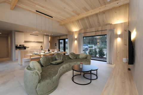 Salon moderne avec cuisine à la Villa Lodge avec jacuzzi chez Woodz Lodges en Belgique, grande baie vitrée.