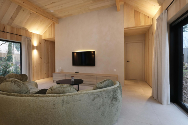 Modernes Wohnzimmer in der Villa Lodge mit Jacuzzi bei Woodz Lodges in Belgien, mit runden Sofas.