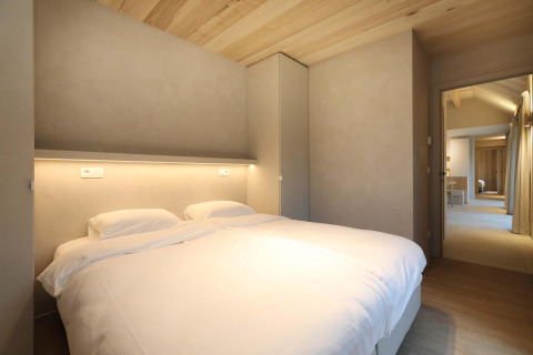 Dormitorio en Villa Lodge con jacuzzi en Woodz Lodges, Bélgica, decoración moderna y techo de madera visible.
