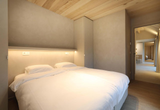 Schlafzimmer in der Villa Lodge mit Whirlpool bei Woodz Lodges in Belgien, modernes Design und Holzdecke.