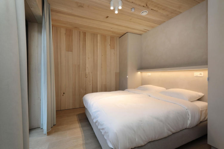 Modernes Schlafzimmer in der Villa Lodge mit Jacuzzi bei Woodz Lodges in Belgien, Holzwände.