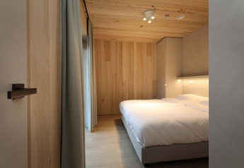Slaapkamer in Villa Lodge met jacuzzi bij Woodz Lodges in België, met houten afwerking en dubbel bed.