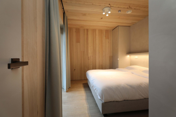 Schlafzimmer der Villa Lodge mit Jacuzzi in den Woodz Lodges, Belgien, mit Holzdesign und Doppelbett.