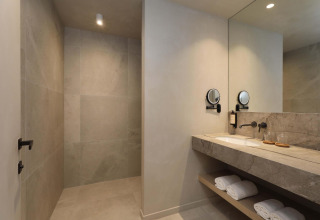 Moderne badkamer van Villa Lodge met jacuzzi bij Woodz Lodges in België, met grote spiegel en douche.