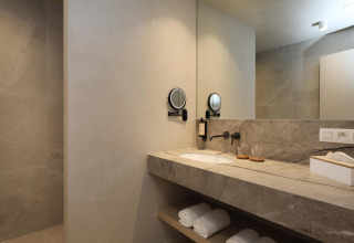 Modernes Badezimmer mit Marmorwaschtisch, Spiegel und Handtüchern in der Villa Lodge mit Jacuzzi, Woodz Lodges, Belgien.