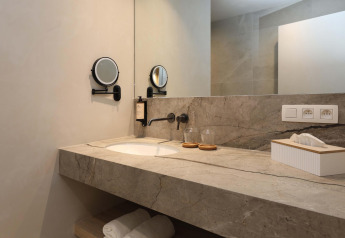 Moderne badeværelsesvask med spejl, vægmonteret armatur og toiletartikler i Villa Lodge med Jacuzzi, Woodz Lodges, Belgien.