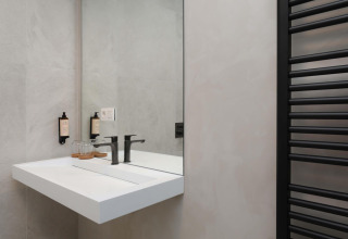 Modernes Badezimmer mit Waschbecken und Spiegel in der Villa Lodge mit Jacuzzi bei Woodz Lodges in Belgien.