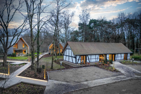 Villa Lodge con jacuzzi en Woodz Lodges, Bélgica, rodeada de bosque y modernas cabañas al atardecer.