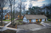 Villa Lodge con jacuzzi en Woodz Lodges, Bélgica, rodeada de bosque y modernas cabañas al atardecer.
