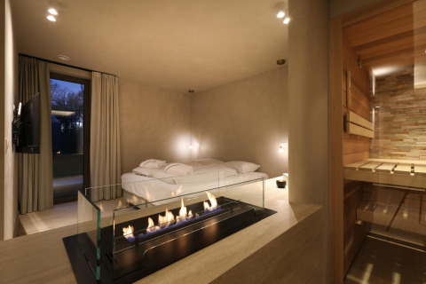 Wellness Suite at Woodz Lodges in Belgium featuring a modern fireplace, cozy bed, and private sauna.