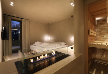 Wellness Suite bij Woodz Lodges in België met moderne haard, comfortabel bed en privé-sauna.