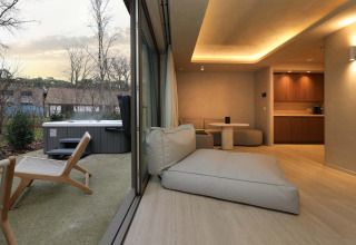 Indoor and outdoor view from Wellness Suite at Woodz Lodges in Belgium, featuring modern décor and hot tub.