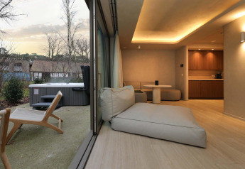 Binnen- en buitenzicht vanuit de Wellness Suite bij Woodz Lodges in België met modern interieur en jacuzzi.