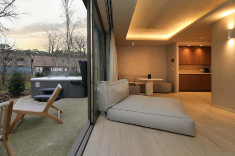 Vista interna ed esterna dalla Wellness Suite presso Woodz Lodges in Belgio con arredo moderno e vasca idromassaggio.