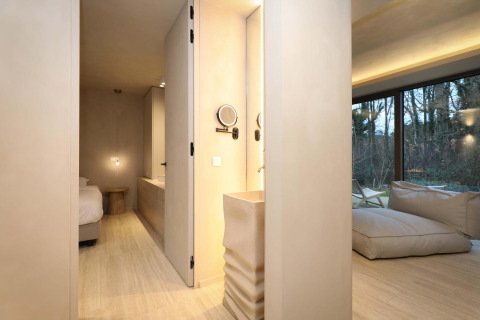 Suite Wellness moderna en Woodz Lodges, Bélgica, con decoración elegante y grandes ventanales al bosque.