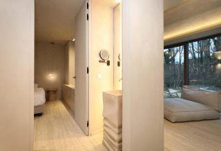 Suite Wellness moderna en Woodz Lodges, Bélgica, con decoración elegante y grandes ventanales al bosque.
