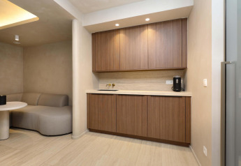 Moderne wellness suite bij Woodz Lodges in België, met houten kasten, zithoek en strak interieur.