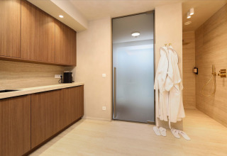 Wellness Suite en Woodz Lodges, Bélgica, con zona de spa moderna, albornoces y armarios de madera.