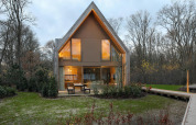 Moderne Lodge bei Woodz Lodges in Belgien mit großen Fenstern, Holzbänken und naturreicher Umgebung.