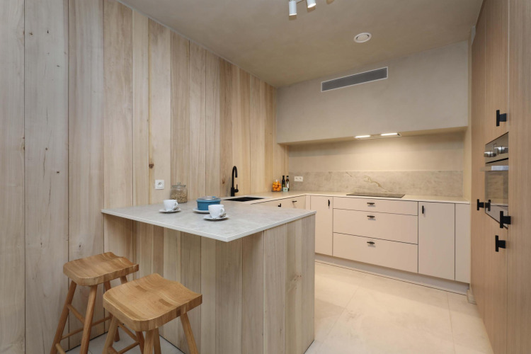 Cocina moderna en Lodge at Woodz Lodges, Bélgica, con madera natural, isla y taburetes.