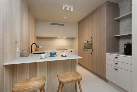 Moderne keuken in Lodge at Woodz Lodges in België met houten wandbekleding, barkrukken en strak design.