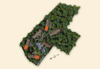 Vista aérea de Lodge at Woodz Lodges en Bélgica, edificios rodeados por bosques y caminos espesos.