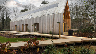 Un lodge moderno in legno con pannelli solari sul tetto, circondato da passerelle e alberi.