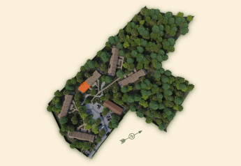 Luftfoto af Group Lodge ved Woodz Lodges i Belgien, omgivet af grønne træer og flere bygninger.