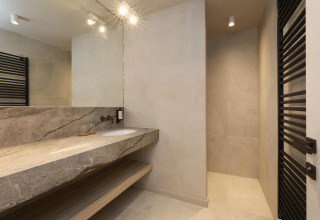 Baño moderno con encimera de mármol, gran espejo y ducha en Lodge at Woodz Lodges en Bélgica.