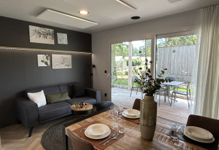 Soggiorno e sala da pranzo moderni nel chalet Domus 4 a Zilverstrand, Belgio, con vista sul patio.