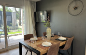 Modern dining area in Domus 4 chalet at Zilverstrand, Belgium, with wooden table, four chairs and wall clock.