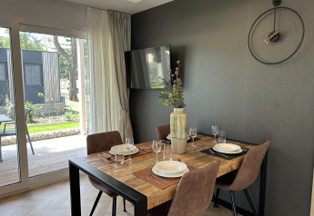 Moderne eethoek in chalet Domus 4 op Zilverstrand, België, met houten tafel, vier stoelen en wandklok.