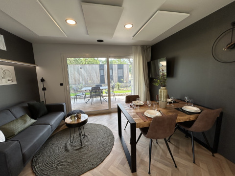 Salon et salle à manger modernes dans le chalet Domus 4 à Zilverstrand, Belgique, avec vue sur la terrasse.