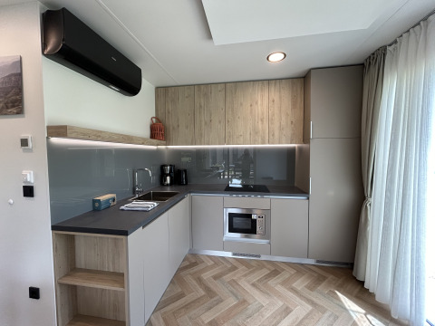 Cuisine moderne de chalet à Domus 4 au Zilverstrand, Belgique, avec placards bois et grande fenêtre.