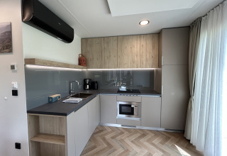 Cuisine moderne de chalet à Domus 4 au Zilverstrand, Belgique, avec placards bois et grande fenêtre.