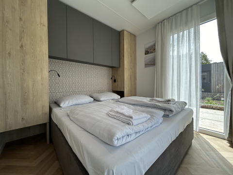 Moderne slaapkamer in chalet Domus 4 op Zilverstrand in België, met tweepersoonsbed en groot raam.